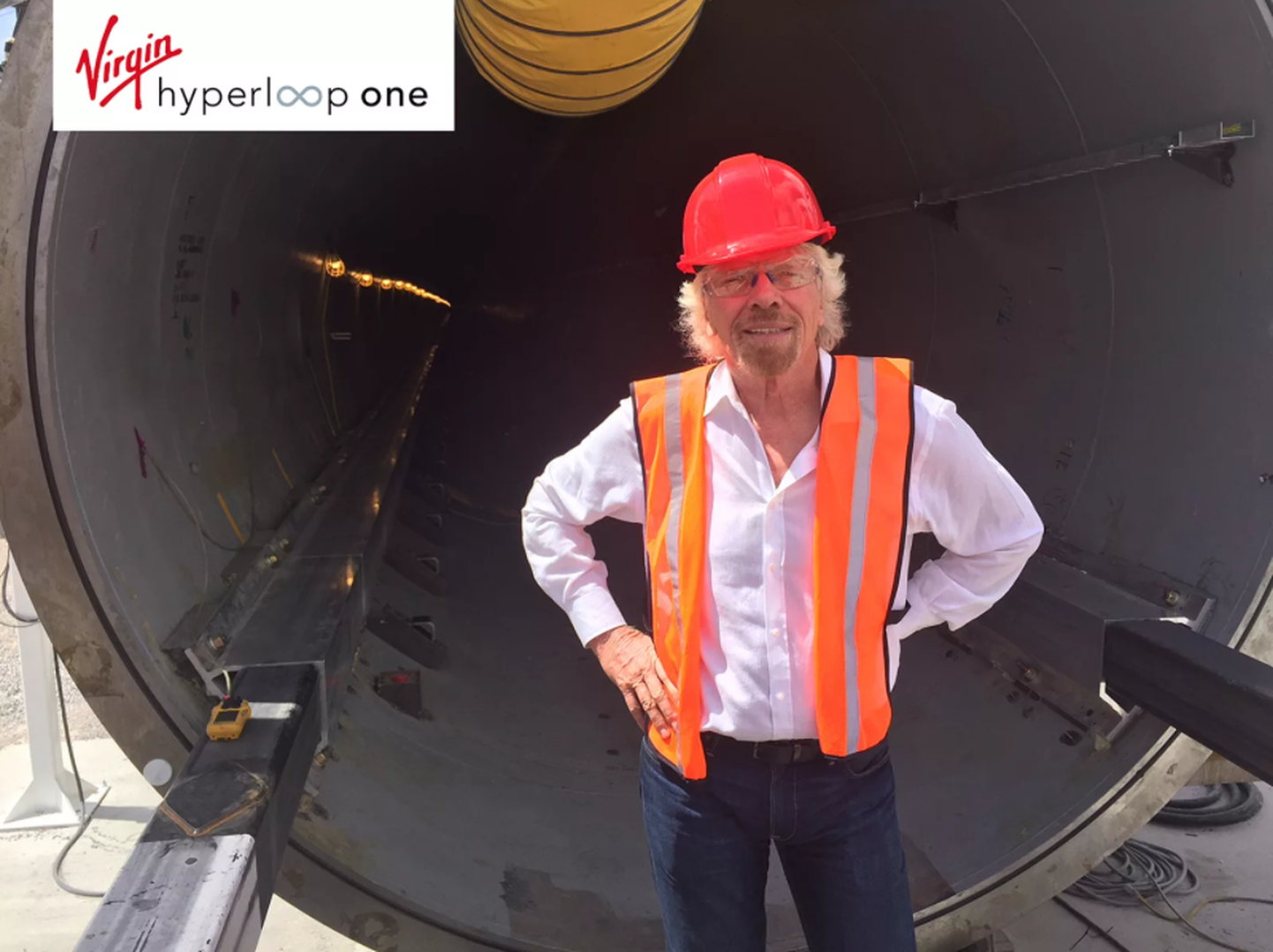 Richard Branson poseerimas Hyperloop One'i tunneli taustal. Pildi ülemisel serval on ka Hyperloop One'i uus logo.