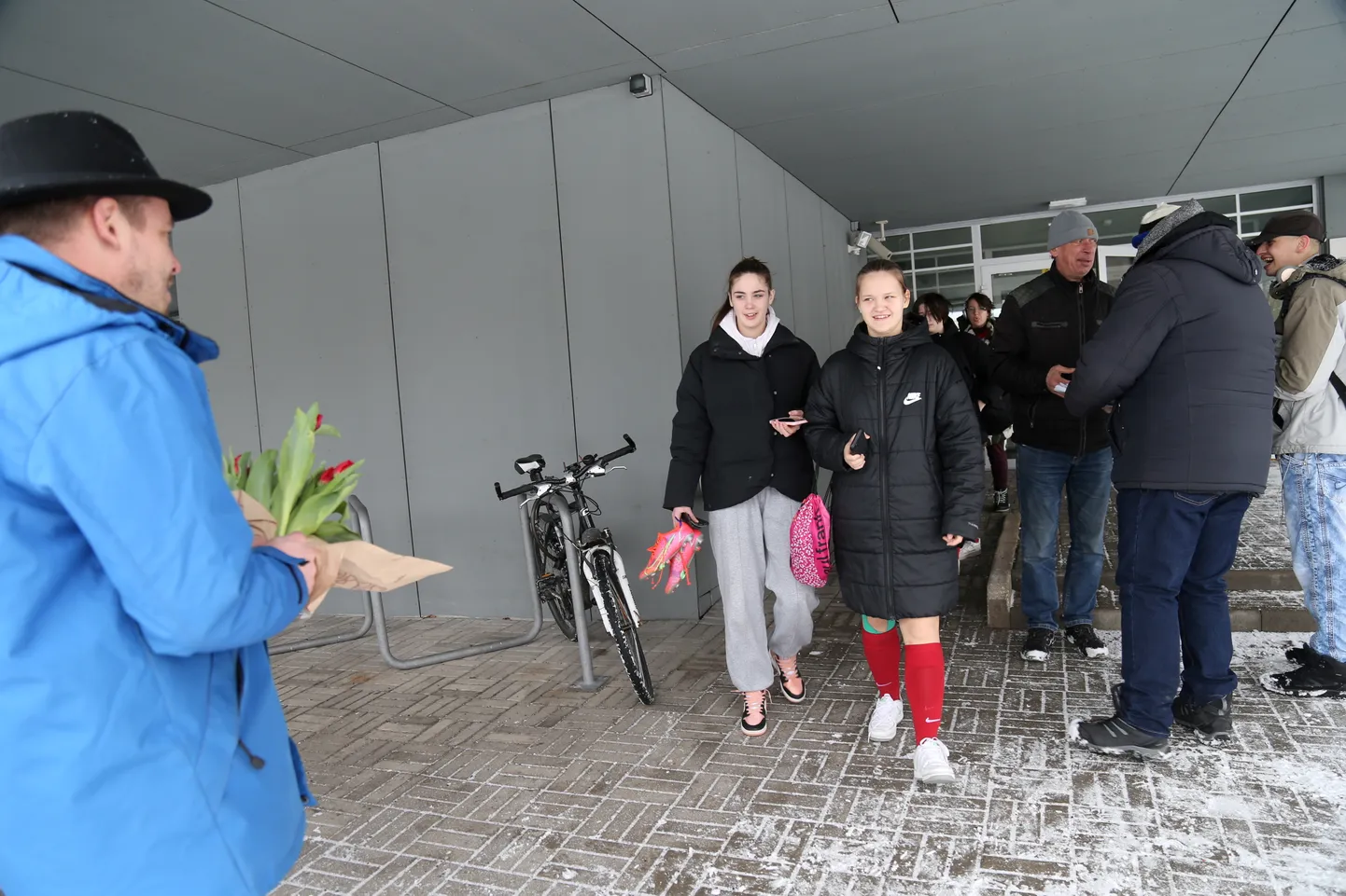 Koolitüdrukud tulevad Petersoni koolimajast trennist ja saavad kingituseks tulbiõie. Paremal paar lõbusas tujus meest valimisbukletti vastu võtmas.