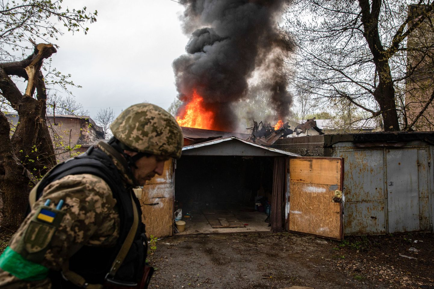 Ukraina sõdur eile Harkivis. Taamal Vene mürsu tabamuse saanud ning põlema süttinud garaaž.