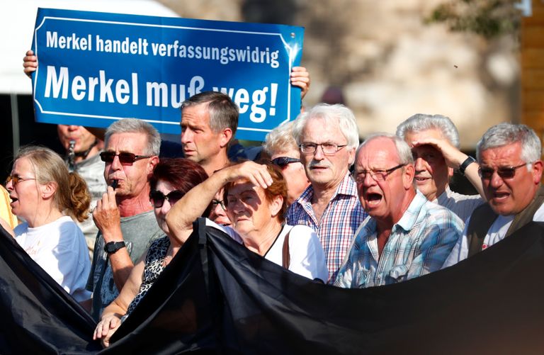 Meeleavaldajad hoiavad käes plakatit kirjaga: «Merkel tegutseb põhiseaduse vastaselt, Merkel peab lahkuma.»