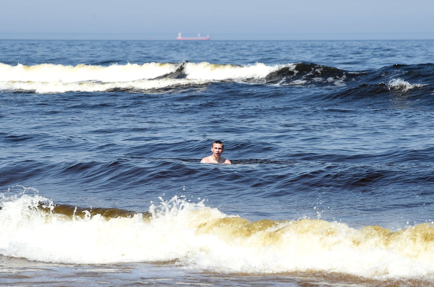 Vīrietis peldas Vecāķu pludmalē.