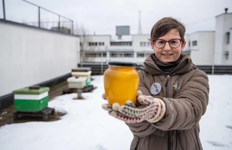 Tallinna Ülikooli teadur Liisa Puusepp ülikooli katusel - vasakul on mesitarud ja käes purk mett, mille kandsid läinud suvel kokku oma maja mesilased.