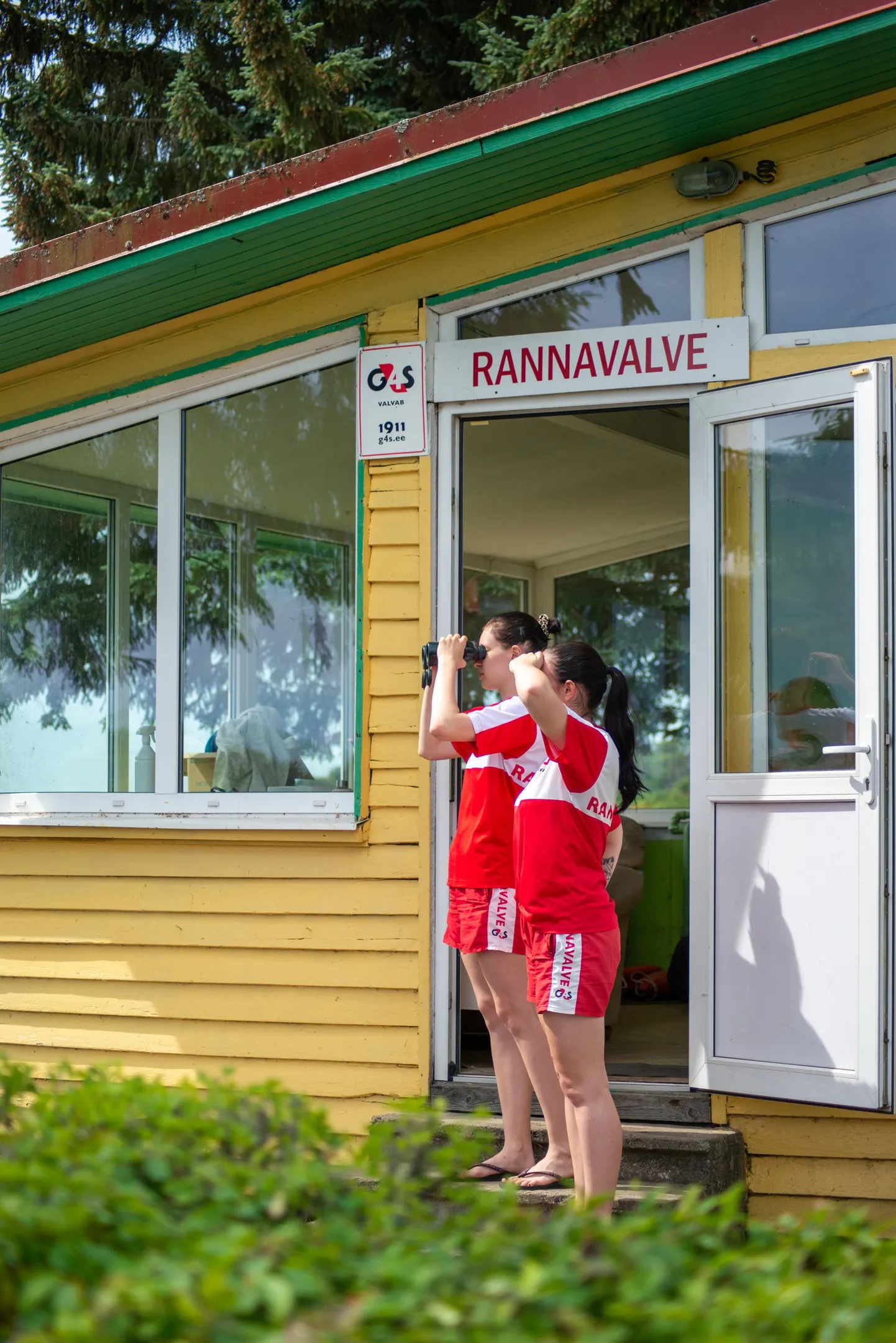 Rannavalvurid jälgivad vetelpäästehoone ees suplejaid.