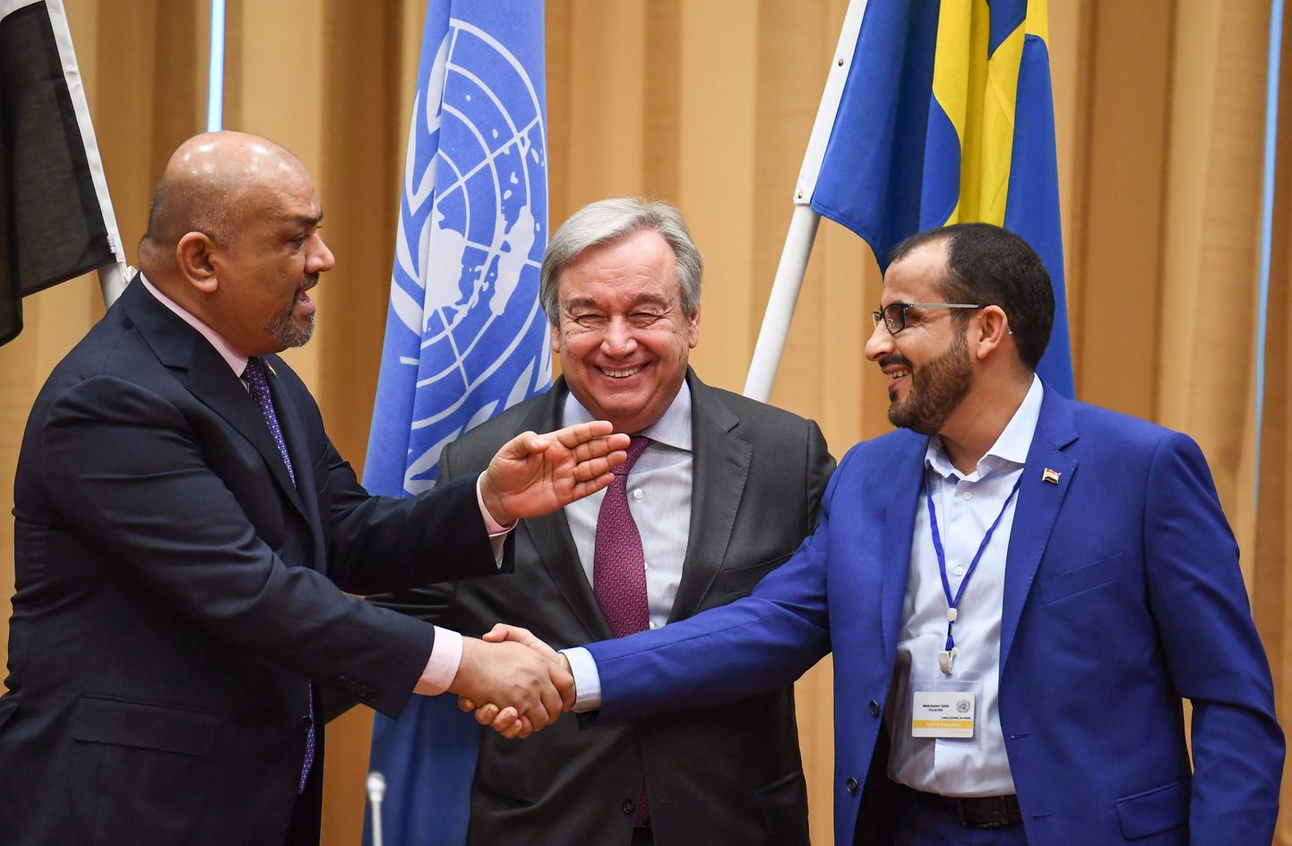 Jeemeni välisminister Khaled al-Yamani (vasakul) ja  šiiamässuliste huthide esindaja Mohammed Abdelsalam (paremal) suruvad ÜRO peasekretäri António Guterres'i silme all kätt.