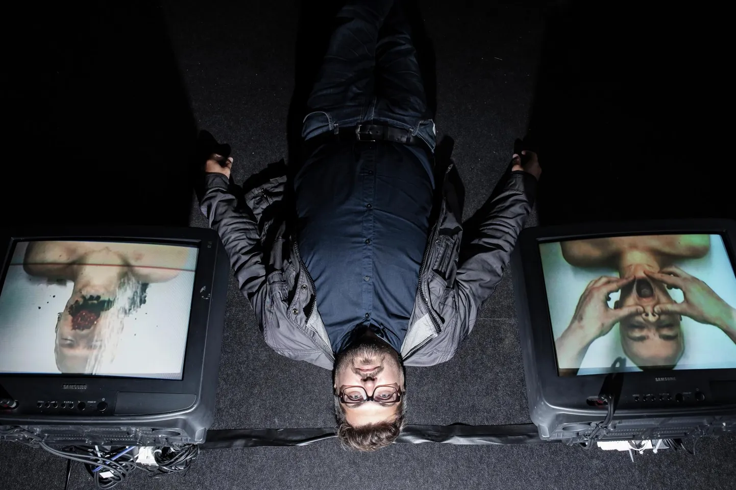 Kuraator Anders Härm EKKMis näitusel XENOS. Pildil lamamas Semperi ja Kiwa videoinstallatsiooniga «Oaas/Oasis».