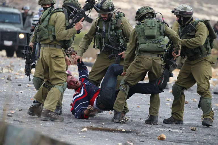 Iisraeli sõdurid Ramallah's viga saanud palestiinlast kinni võtmas.