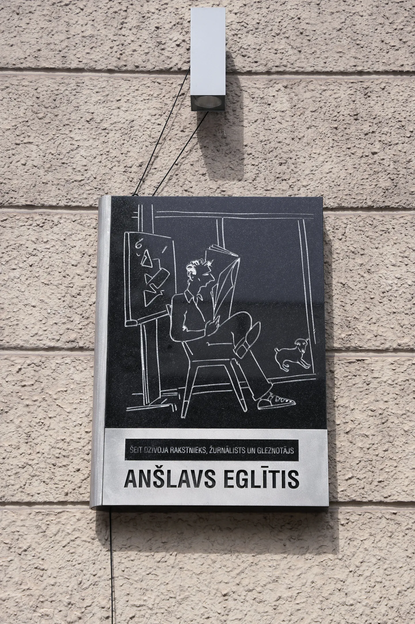 Skices un plāksnes autors ir tēlnieks Kristaps Gulbis, kurš to izgatavojis, balstoties uz rakstnieka pašportretu, kas izvēlēts, pārskatot apmēram 100 attēlus.