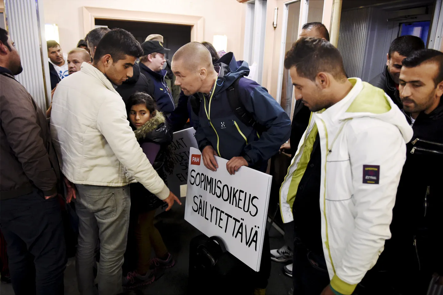 Ametiühingu liikmed teel Helsingisse streikima. Silti vaatab Iraagist sisserännanu.