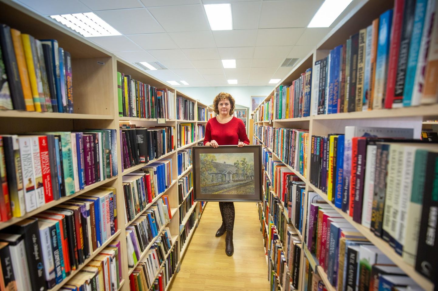 Tarvastu raamatukogu direktor Aili Anderson hoiab käes maali, millel on kujutatud kunagist Tarvastu valla- ja kohtumaja. 