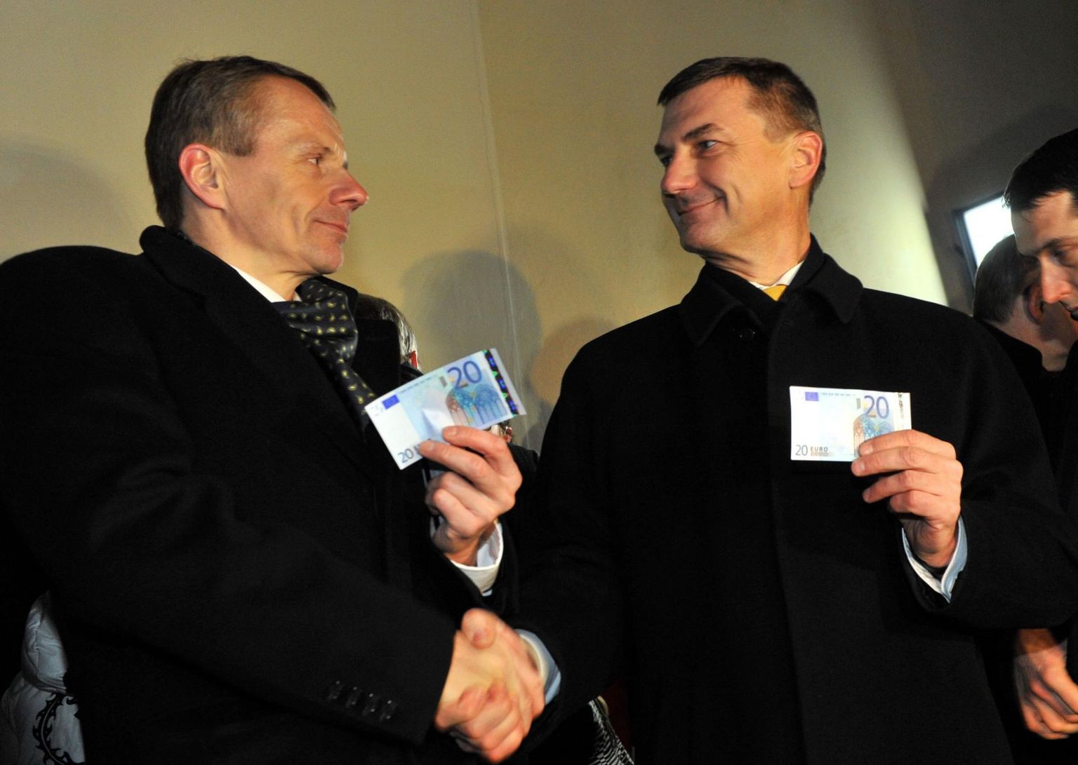 Toonane peaminister Andrus Ansip ja rahandusminister Jürgen Ligi poseerivad 1. jaanuaril 2011 uue valuutaga.