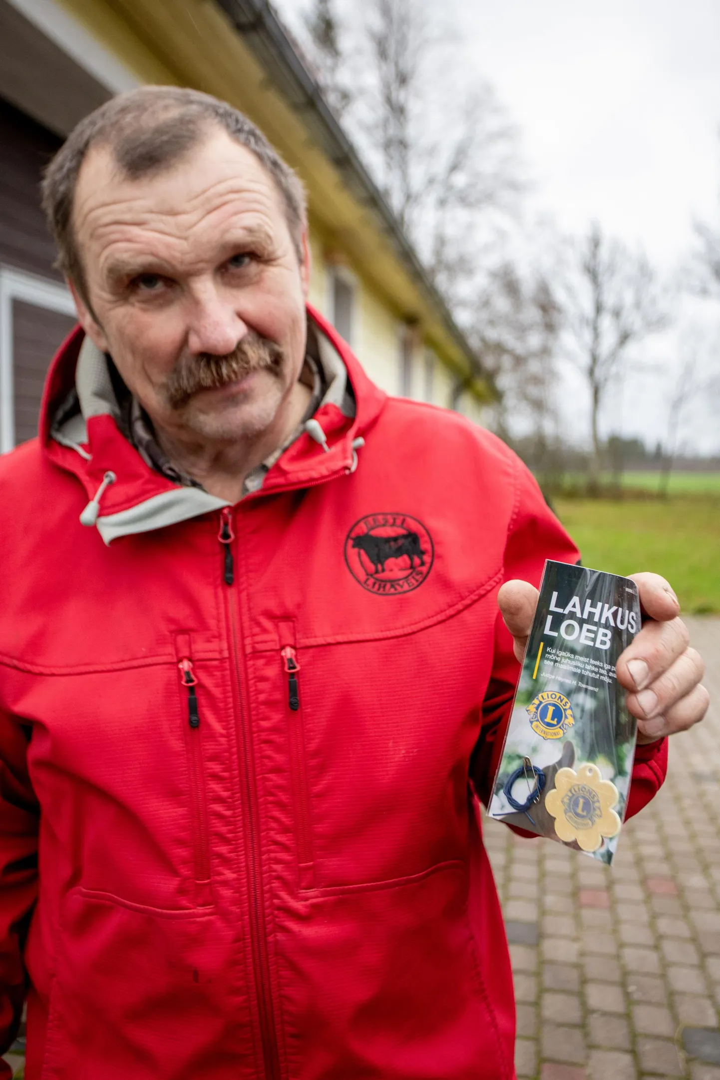 Lihula Lions-klubi president Aldo Vaan näitab mudilas­tele kingitavat helkurit, mille südamikus on Lions Inter­nationali logo.