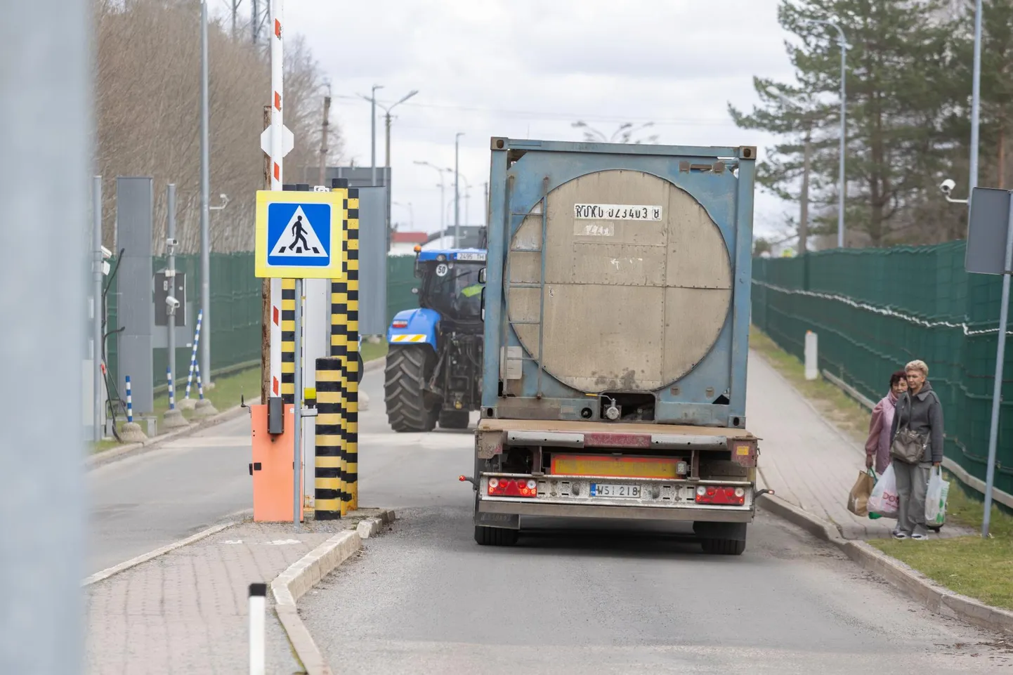 Soome numbrimärgiga veok on saanud rohelise tule, et liikuda kitsal, kõrge traataiaga piiratud teel Luhamaa piiripunktist Venemaa poole. Kõnniteel astuvad Eestisse kaks jalgsi Venemaalt tulijat.