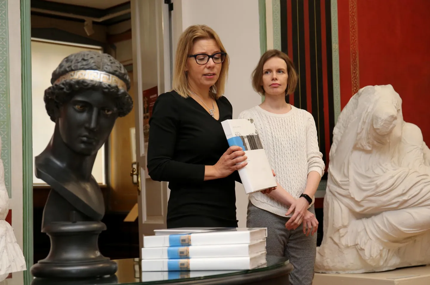 Albumi «Ars academica. Tartu Ülikooli 100 kunstiteost» koostajad Ingrid Sahk (vasakul) ja Moonika Teemus tutvustasid albumit laua juures, mille peal oli raamatute kõrval Athena Lemnia büsti patineeritud kipskoopia. Albumis on selle foto esitatud saja teose hulgas esimesena.