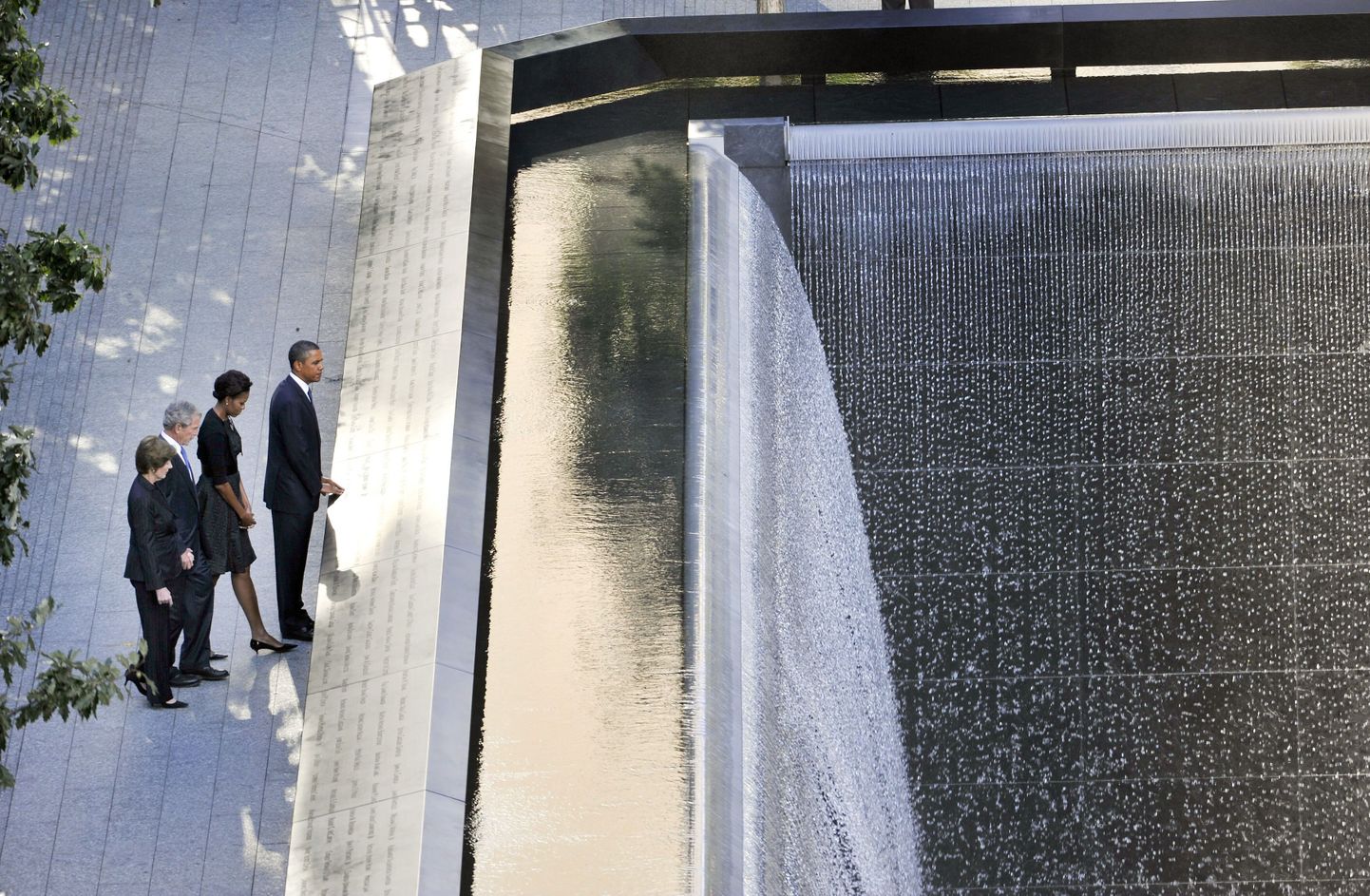 Президент США Барак Обама с супругой Мишель Обамой (справа) и экс-президент Джордж Буш-младший с супругой Лаурой Буш у мемориала, на плитах которого выгравированы имена жерт теракта.