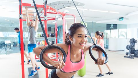 Fit young woman exercising with gymnastic rings in a trendy fitness Fit young woman exercising with gymnastic rings in a trendy fitness