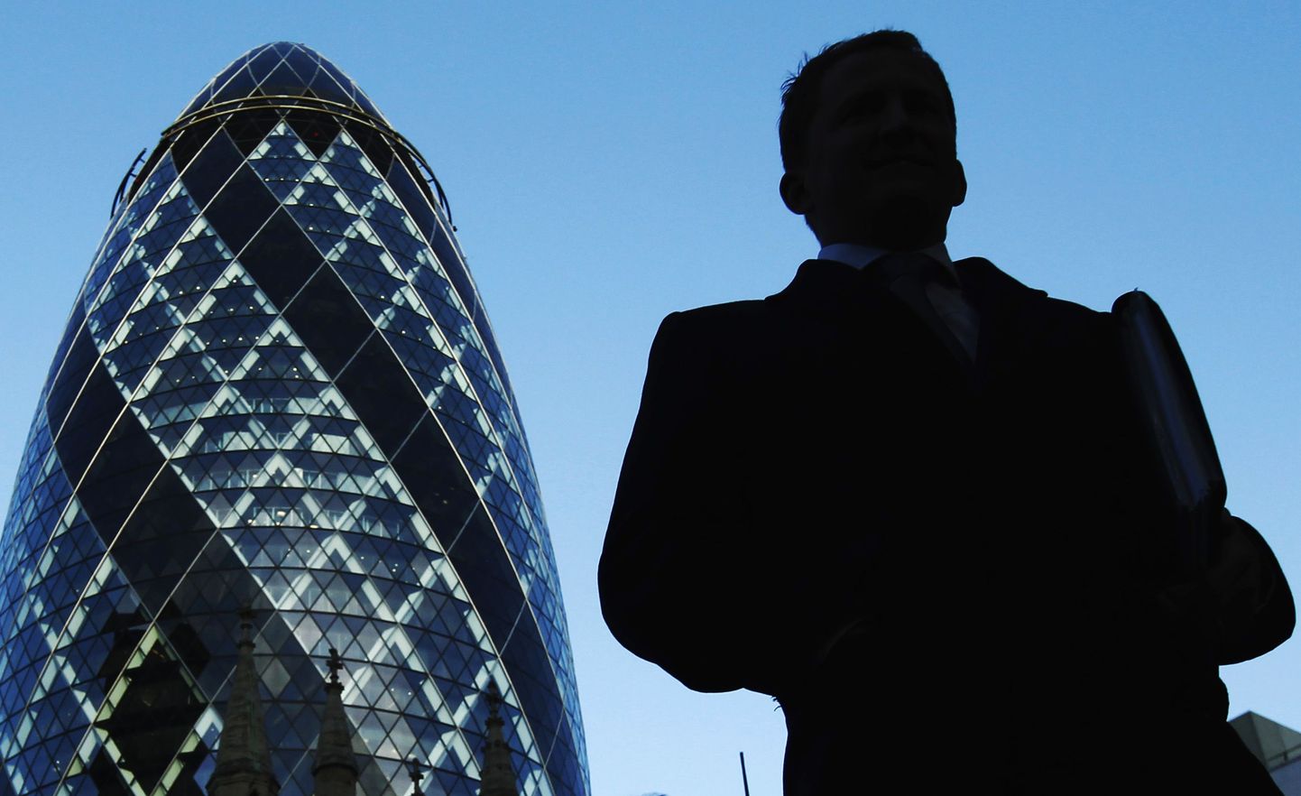 A City worker walks near the Swiss Re building known as the Gherkin in the City of London December 9, 2011.  Europe secured an historic agreement to draft a new treaty for deeper economic integration in the euro zone on Friday, but Britain, the region's third largest economy, refused to join the other 26 countries in a fiscal union and was isolated.   REUTERS/Luke MacGregor  (BRITAIN)