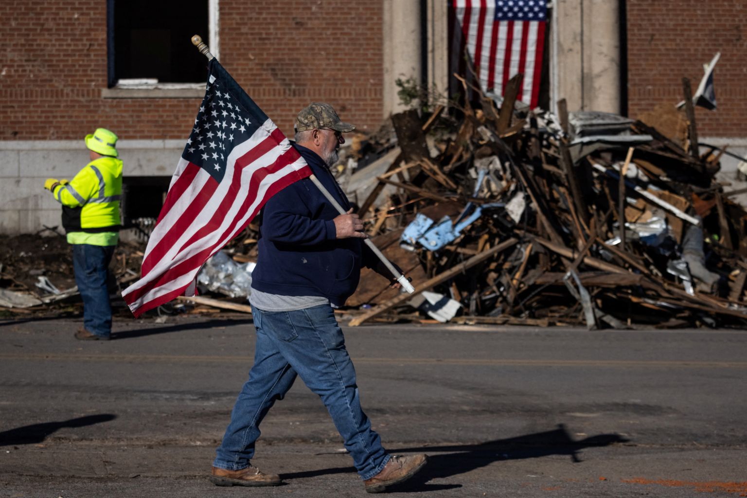 Mees kõndimas Kentuckys Mayfieldis pärast tornaado laastamistööd USA lipuga