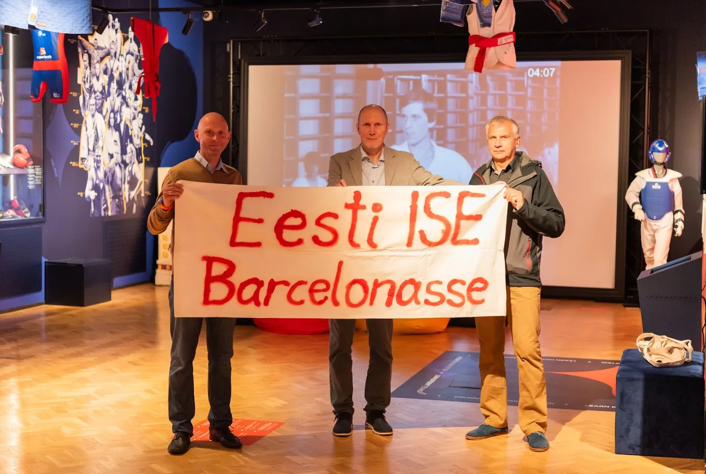 Lipu loojad Erki Jaanson, Jaanus Terik ja Hendrek Kelder selle üleandmisel spordimuuseumis.