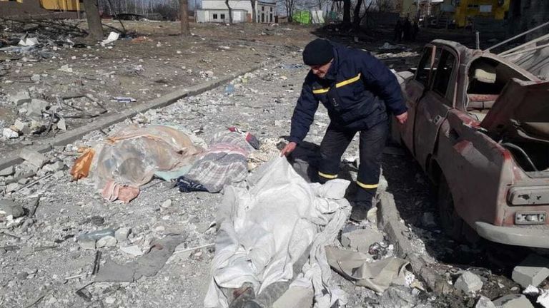 Сотрудник МЧС Украины накрывает тело человека, погибшего в результате российского обстрела в Чернигове, 17 марта