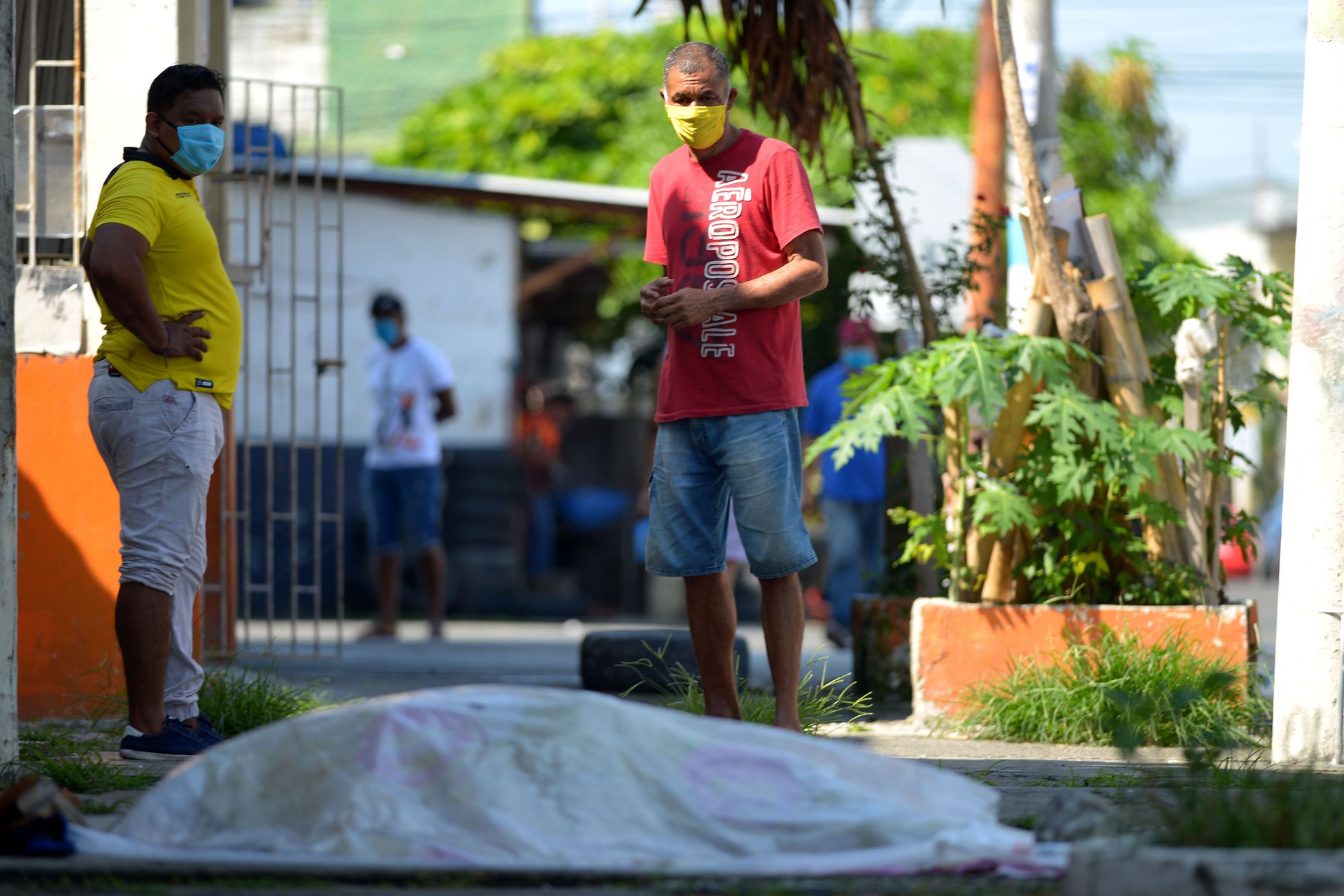 Gvajakilas iedzīvotāji skatās uz ceļa malā atstātu līķi.