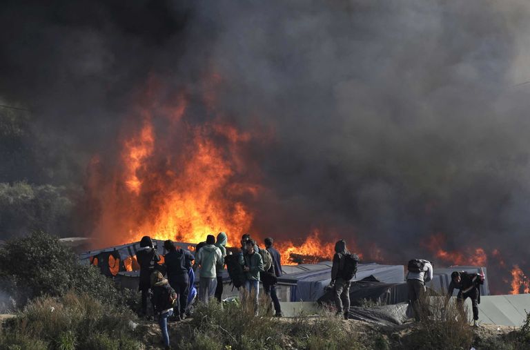 Thick smoke and flames rise from amidst the tents after fires were started in the makeshift migrant camp known as "the jungle" near Calais, northern France, Wednesday, Oct. 26, 2016. Firefighters have doused several dozen fires set by migrants as they left the makeshift camp where they have been living near the northern French city of Calais. (AP Photo/Emilio Morenatti)