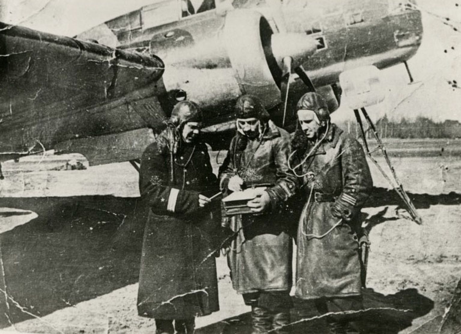 BERLIINI POMMITAMISEST osavõtnud laskurradist V. M. Krotenko 1942. a Novinki lennuväljal kaugpommitaja DB-3 taustal (paremal). Vasakul A. T. Drozdov, keskel N. D. 
Kotov.