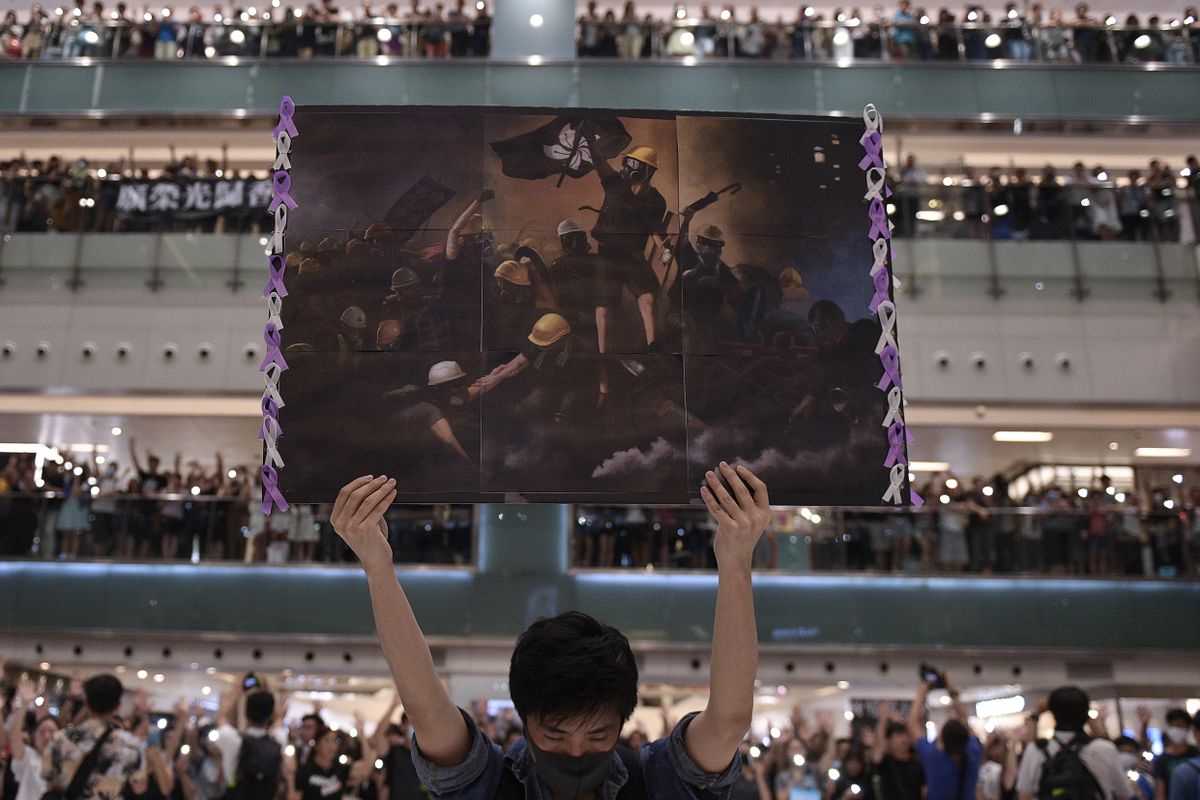 Hongkongis Shatinis hoiab mees plakatit, samal ajal laulavad inimesed protestilaulu «Au Hongkongile», millest kujunes linna mitteametlik hümn.