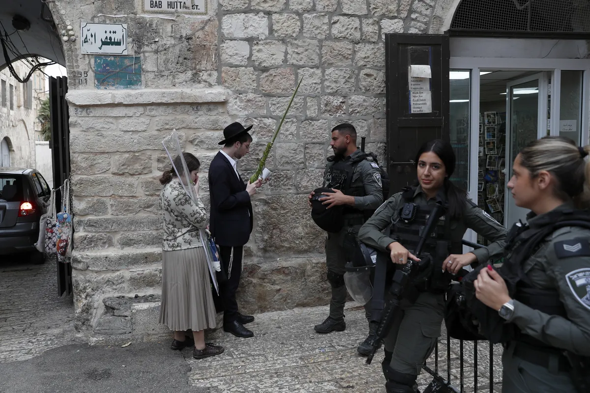Ультраортодоксальные евреи молятся у ворот Баб-Хутта, ведущих к мечети аль-Акса, во время Праздника кущей в Старом городе Иерусалима, 4 октября 2023 года.