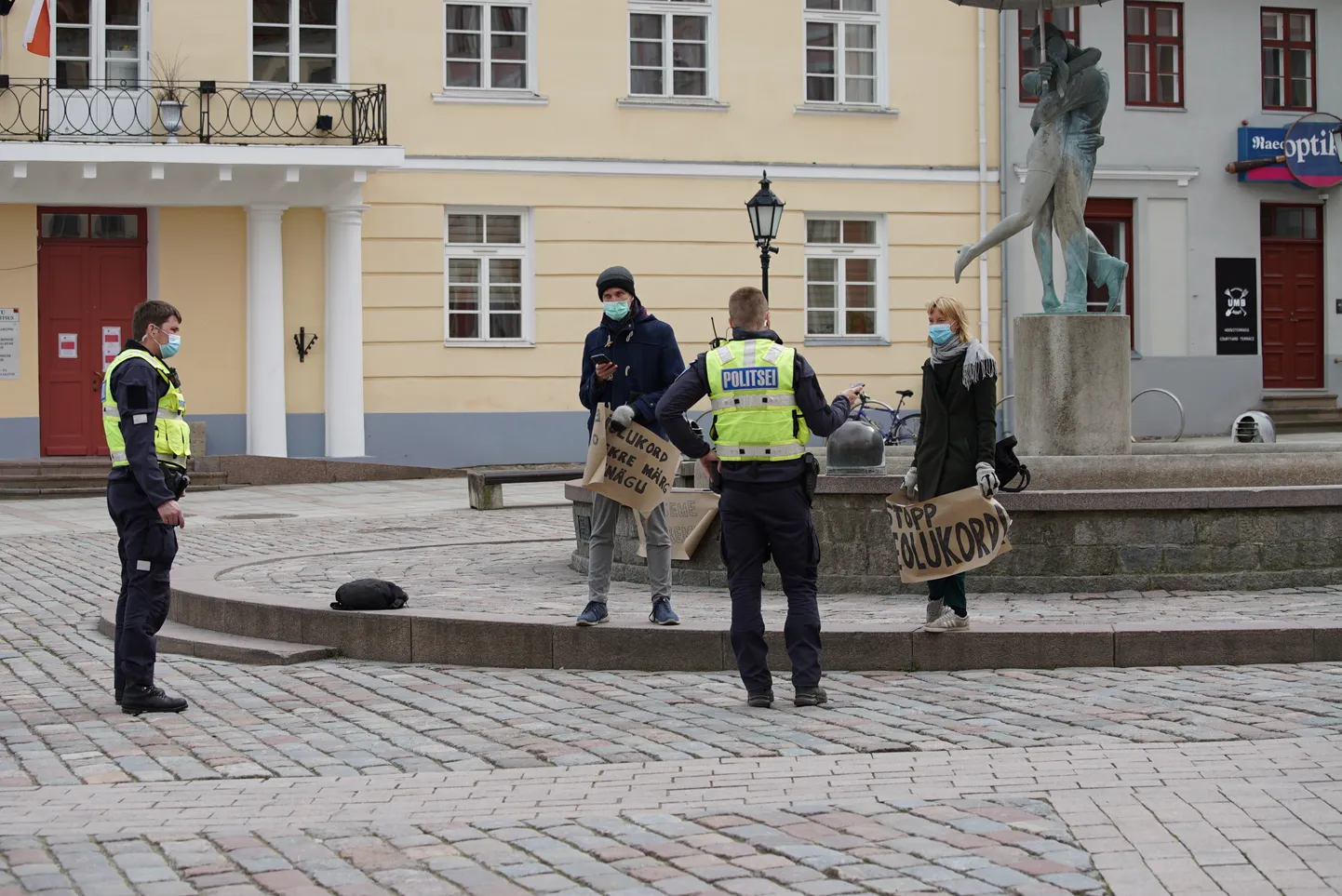 Politseinikud vestlevad plakateid hoidnud neiu ja noormehega.