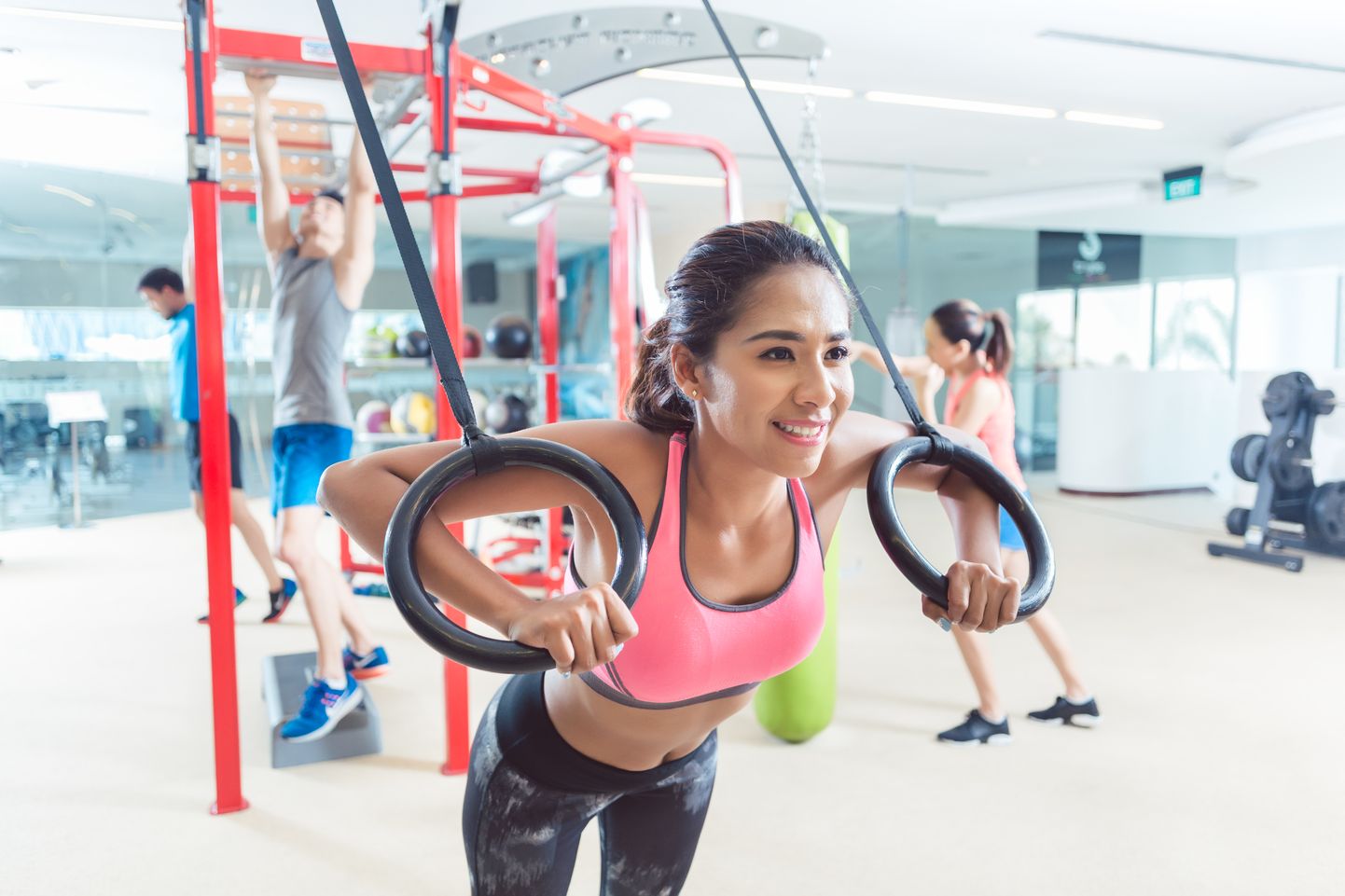 Fit young woman exercising with gymnastic rings in a trendy fitness