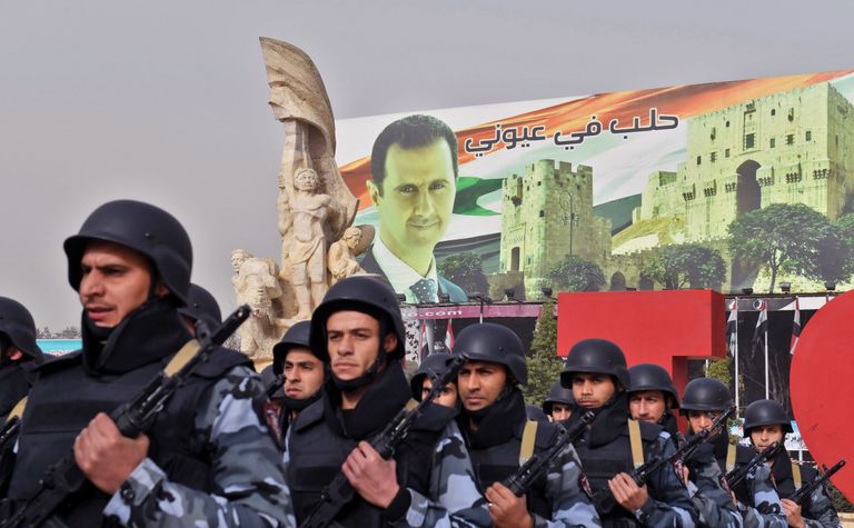 Süüria sõdurid marsivad mööda president Bashar al-Assadi plakatist.