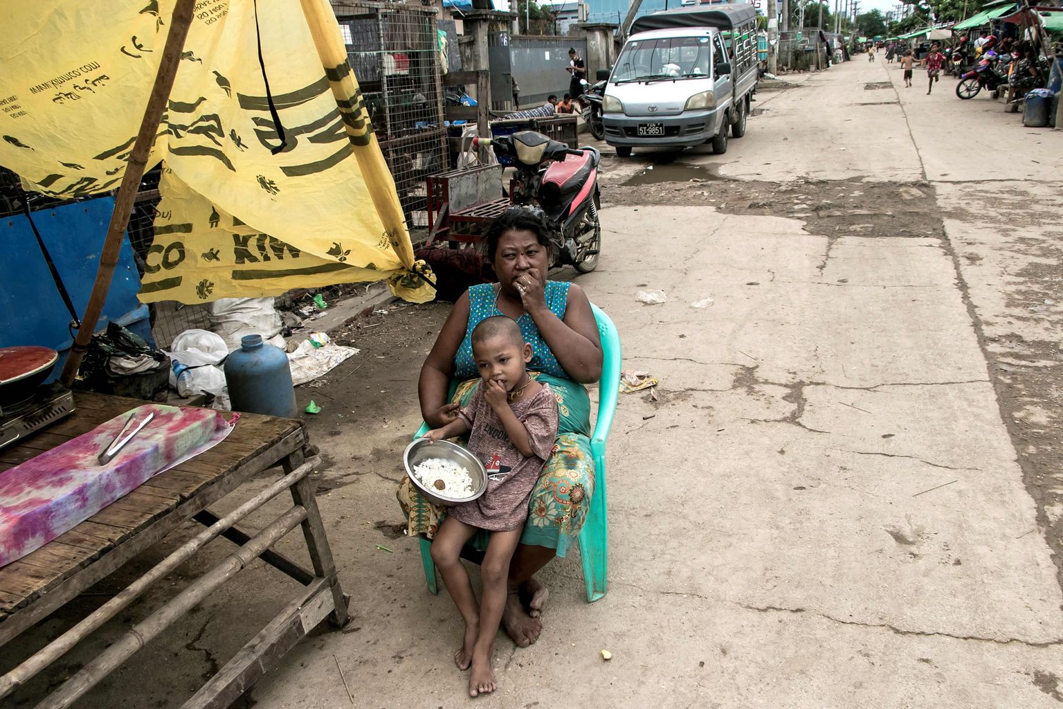 Ema ja laps söövad kodu ees Yangoni äärelinnas.