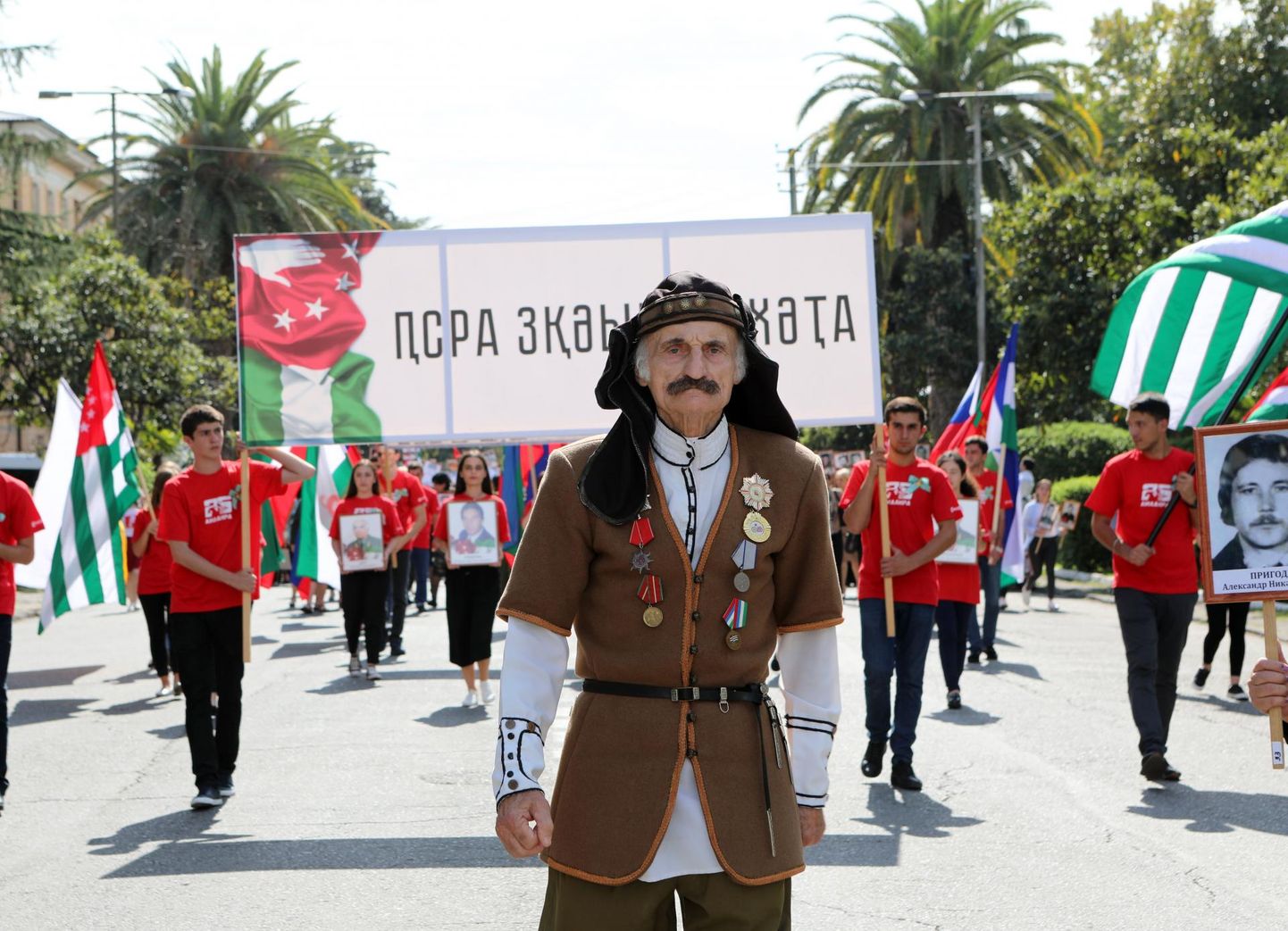Abhaasia sõja võidu 25. aastapäeva tähistamine Suhhumis. Abhaasia sõja veteran rahvuslikus kostüümis juhtimas Abhaasia lippe lehvitavate noorte aktivistide kolonni.