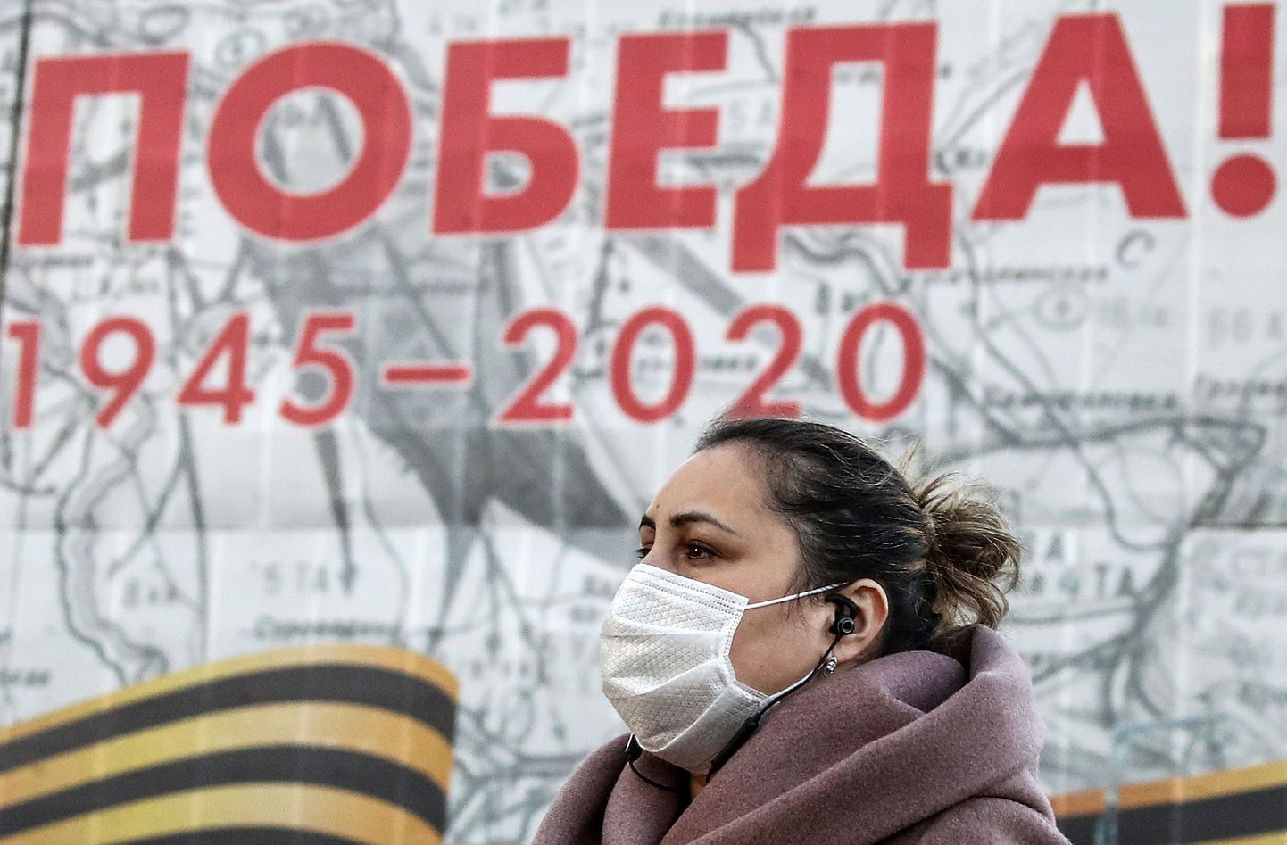 Näomaskiga naine võidupüha lähenemist kuulutava plakati taustal Moskvas.