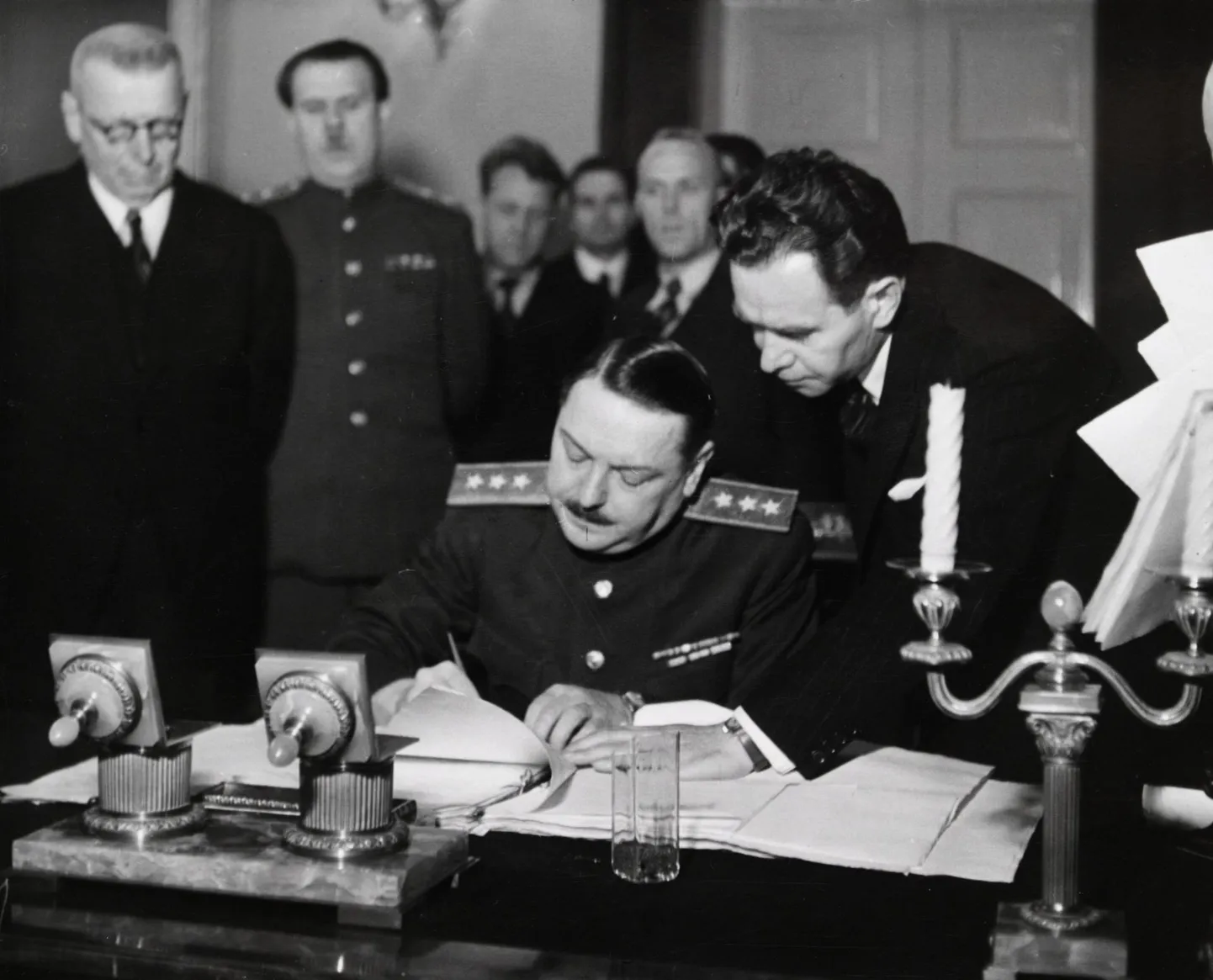 Liitlaste järelevalvekomisjoni esimees Andrei Ždanov (keskel) allkirjastamas 17. detsembril 1944 Helsingis lepingut, mille alusel pidi Soome Nõukogude Liidule tasuma 300 miljoni dollari ulatuses sõjakahjusid. Vasakul seisab Soome peaminister Juho
Kusti Paasikivi.