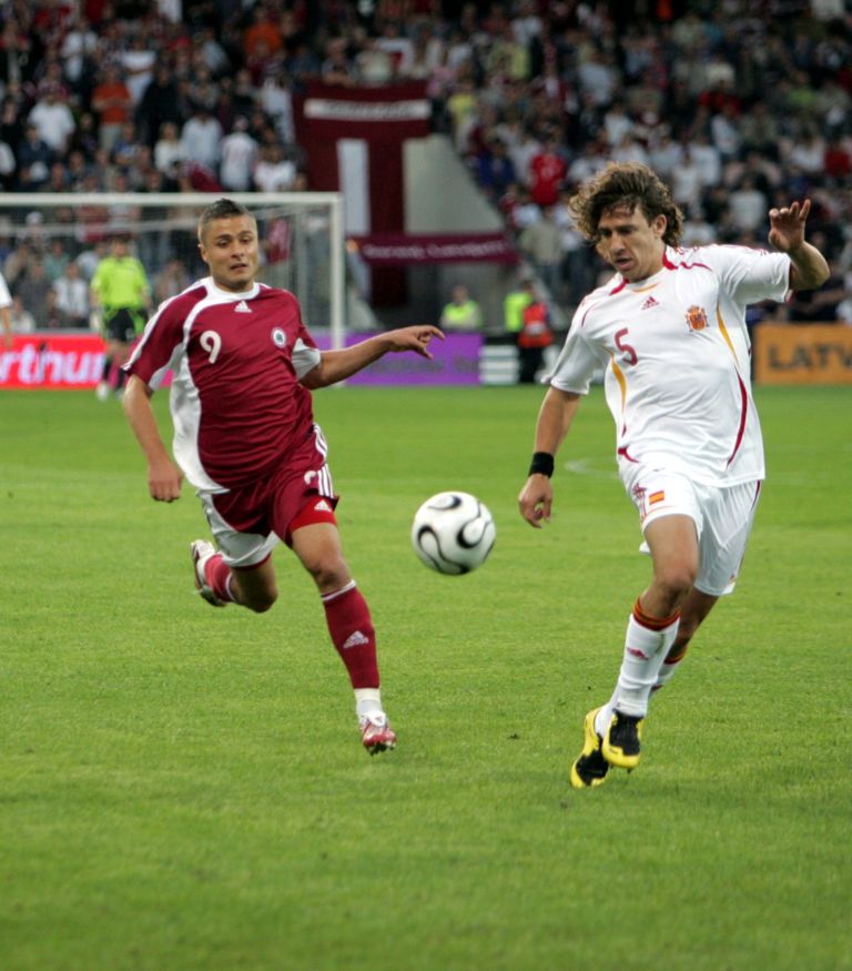 Latvijas futbola izlases uzbrucējs Māris Verpakovskis (nr. 9, sarkans) un Spānijas izlases aizsargs Karloss Pujols (nr. 5, balts) 2008.gada Eiropas futbola čempionāta kvalifikācijas turnīra spēlē "Skonto" stadionā.