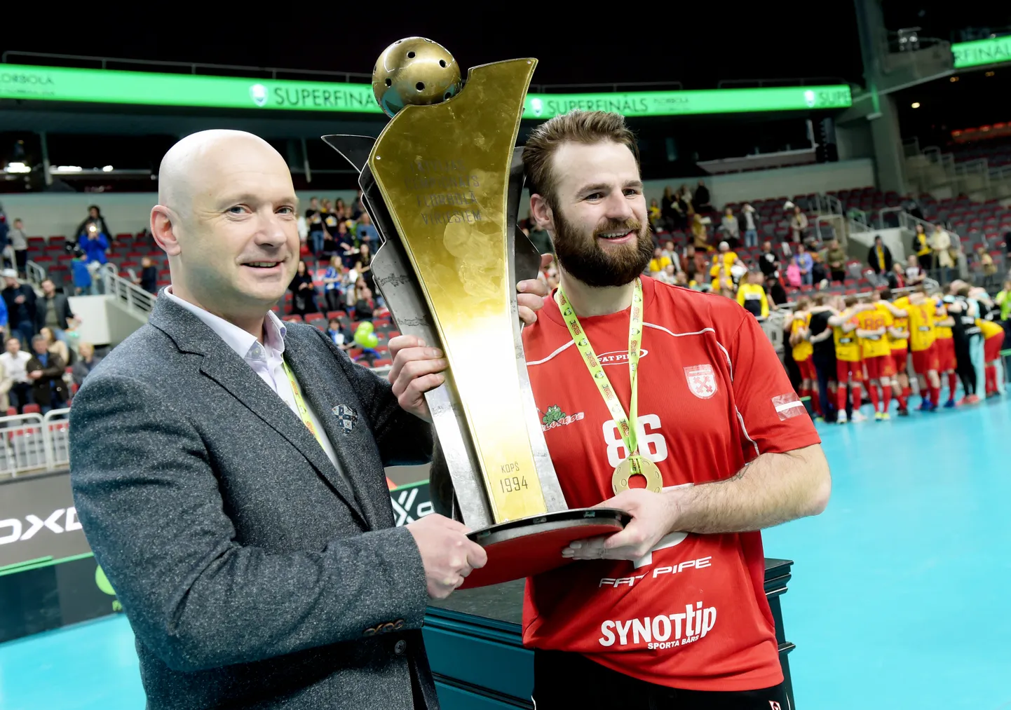 Ilvis Pētersons (no kreisās) un Kaspars Mudelis ar Latvijas florbola virslīgas čempionu kausu