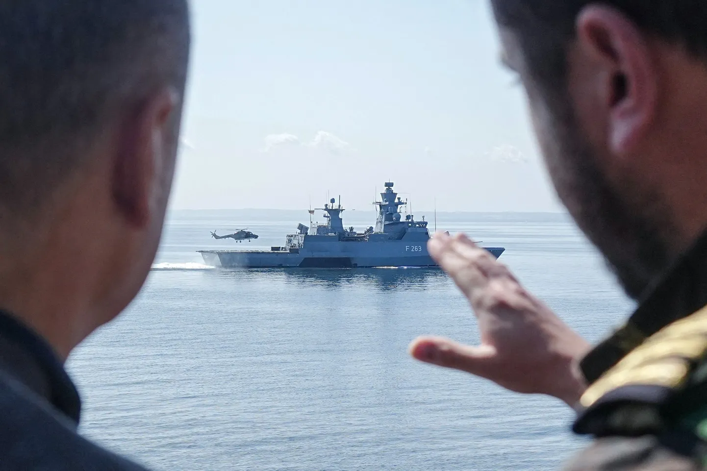 Канцлер Германии Олаф Шольц (слева) разговаривает с военнослужащим, стоя на борту фрегата «Мекленбург-Передняя Померания» во время своего общения с ВМС Германии, чтобы посмотреть, как вертолет приземляется на борту немецкого корвета «Ольденбург» (F263) во время военных маневров в Балтийском море у побережья Росток-Варнемюнде на северо-востоке Германии, 5 июня 2023 года.