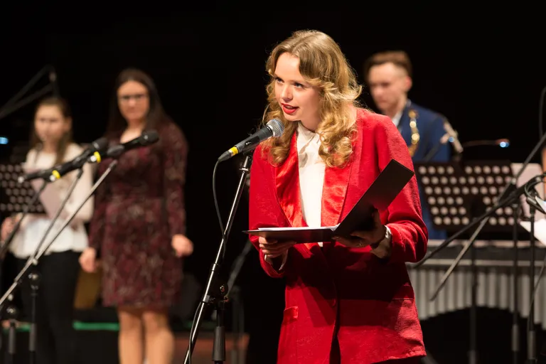 Üks kontserdi konferansjee oli Kohtla-Järve gümnaasiumi särav eesti humanitaarainete õppetooli juhataja asetäitja, eesti keele ja kirjanduse õpetaja Eliisa Puudersell.