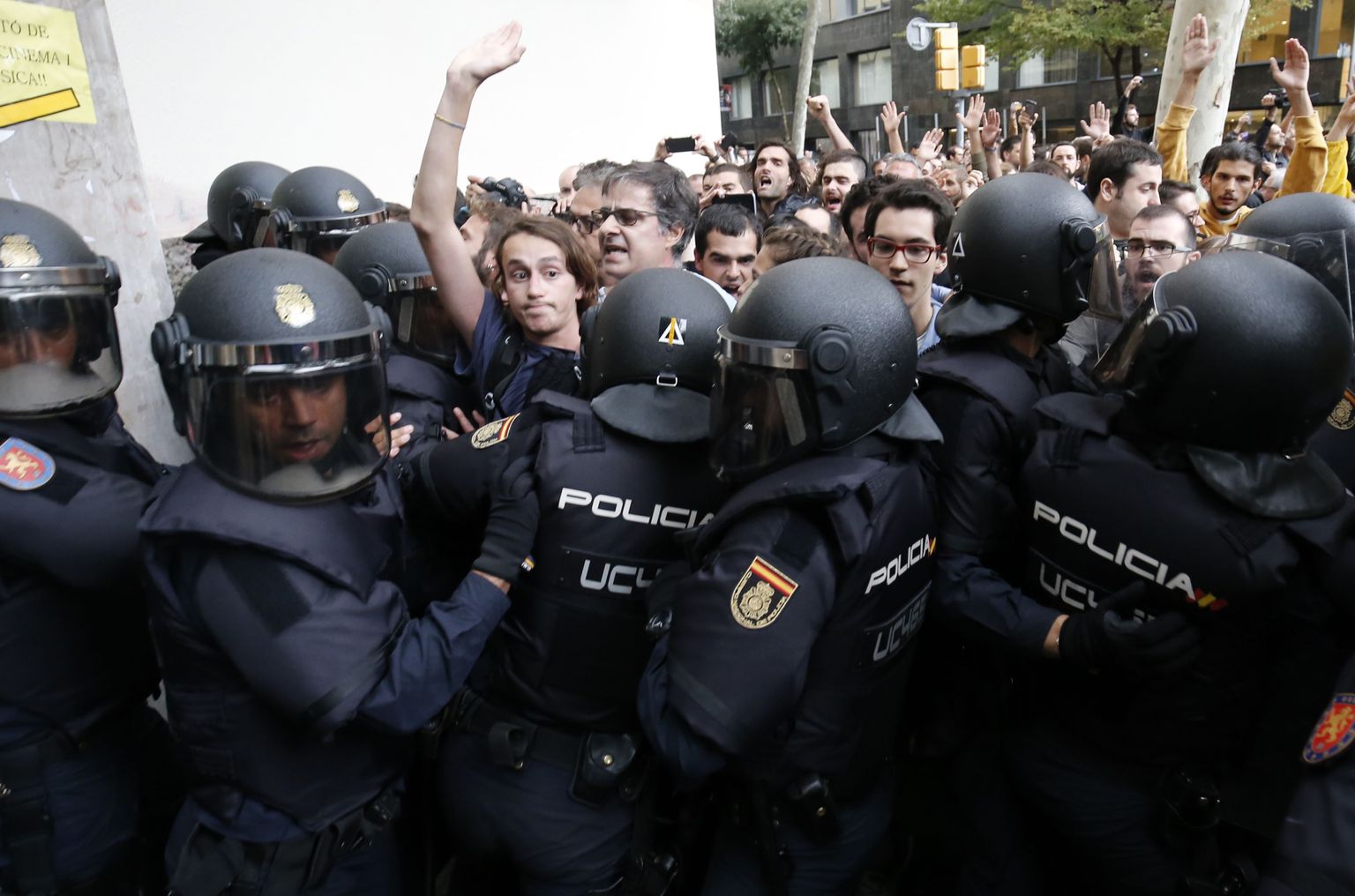 Põhiseaduse nimel tegutsevad politseinikud hoidmas tagasi meeleavaldajaid ühe Barcelona valimisjaskonna juures.
