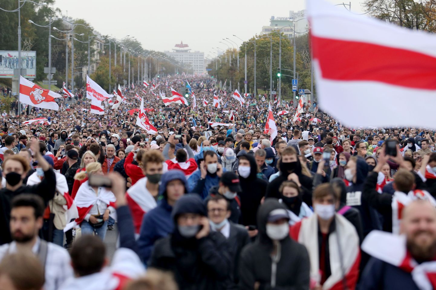Opposition supporters carry the former white-red-white flag of Belarus as they march during a rally to protest the country's presidential inauguration in Minsk on September 27, 2020. - Belarus police on September 27 arrested dozens of people during an opposition march days after the strongman president staged a secret inauguration. The opposition movement calling for an end to the president authoritarian regime has kept up a wave of large-scale demonstrations every Sunday since his disputed win of an August 9 election. (Photo by - / TUT.BY / AFP)