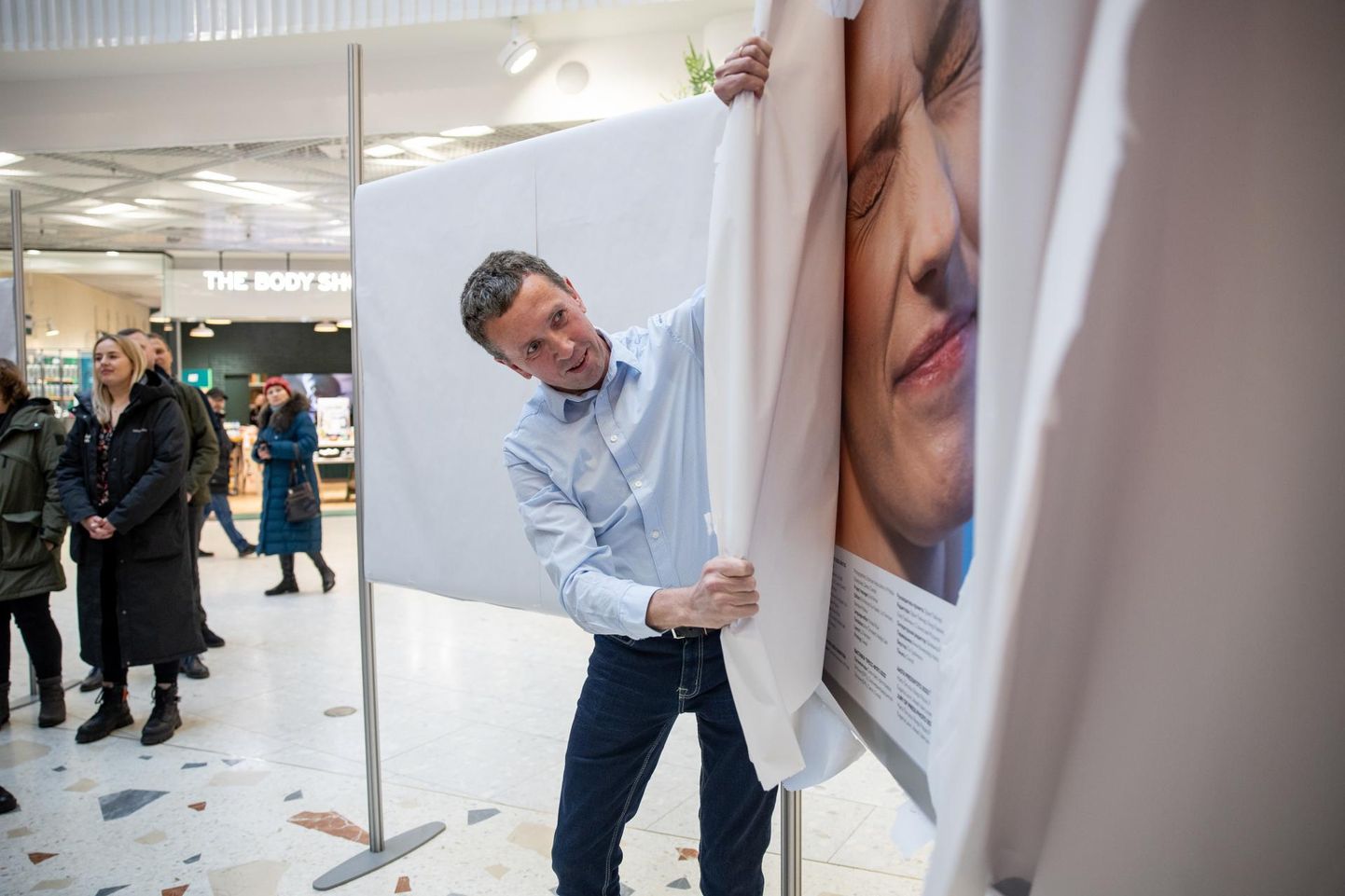 Näituse «Eesti pressifoto 2023» avamine Viru keskuses. Tairo Lutter rebib paberit võidupildilt.

 