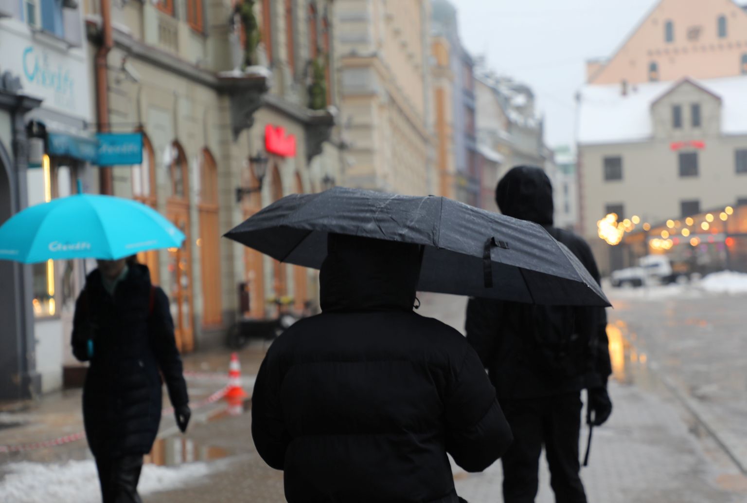 Cilvēki ar lietussargiem Kaļķu ielā.