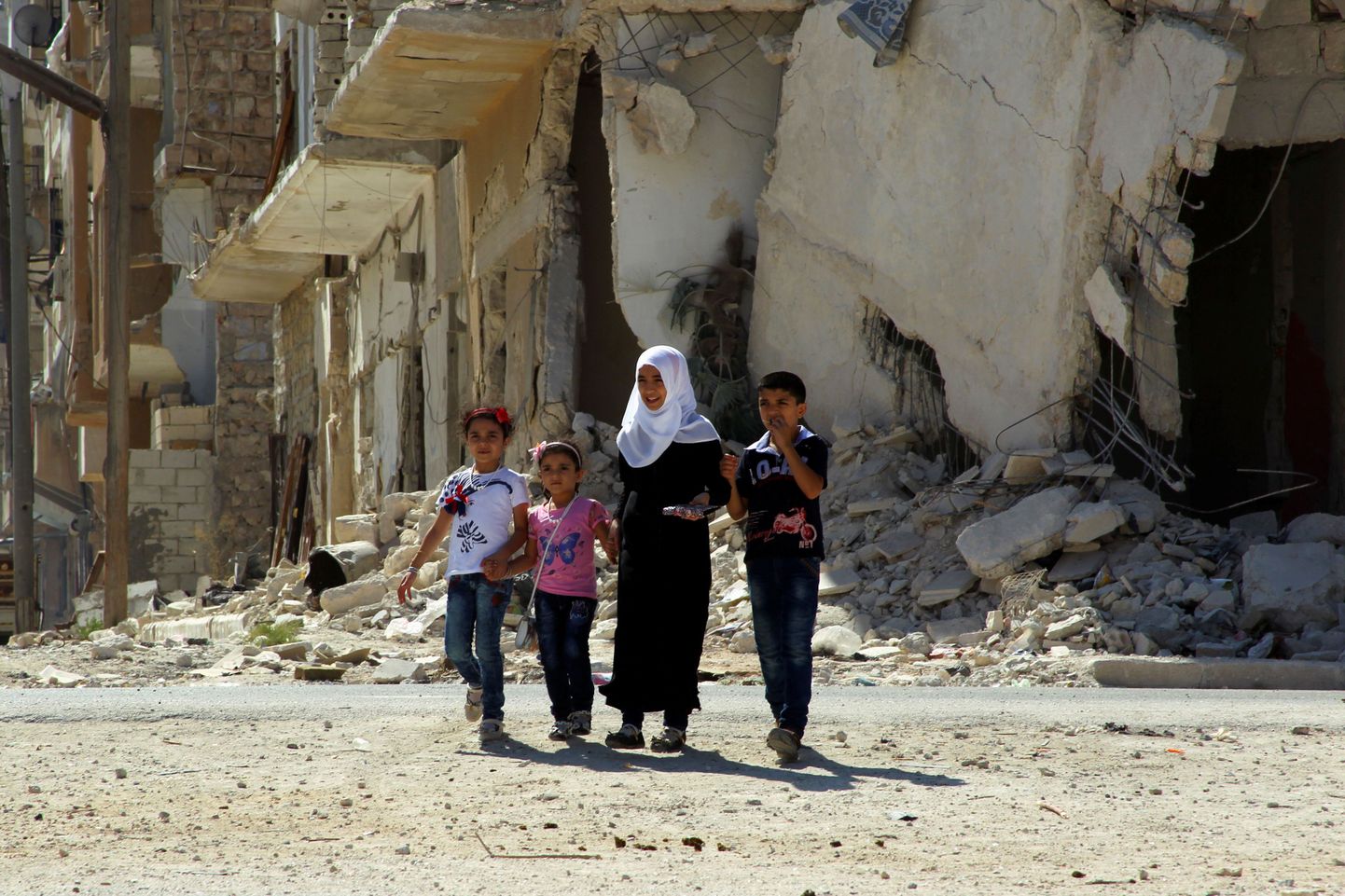 Lapsed jalutamas mässuliste kontrolli all olevas Idlibi linnas õhurünnakutes varemeteks pommitatud majade vahel.