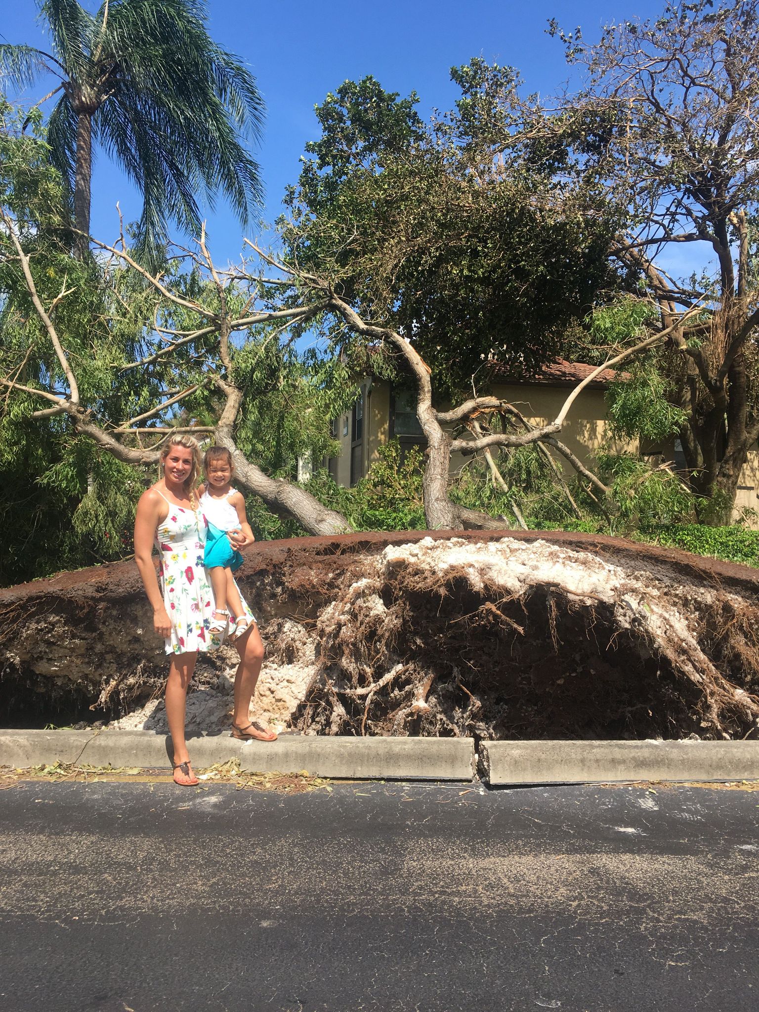 Merle Liivand koos naabri tütre Daphine'iga pärast orkaan Irma vaibumist oma maja lähedal tuulte üleskistud puu kõrval.