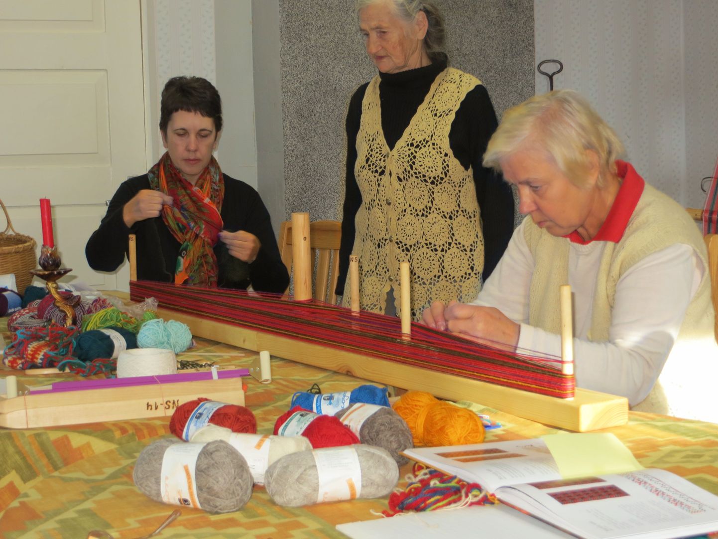 Karula naisseltsi ruumides õppisid käsitööhuvilised naised laupäeval lapivööd tegema. Koidu Ahk (vasakult), Eha Saan ja juhendaja Virve Niilisk sätivad käärlauale vöölõimeid.