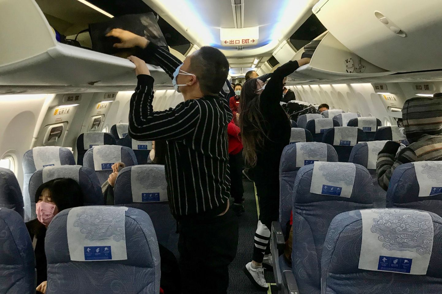 Näomaske kandvad reisjad täna Wuhani lennujaamas maandunud õhusõidukis. Võimud on otsustanud peatada lennukite ja rongide lahkumise linnast.