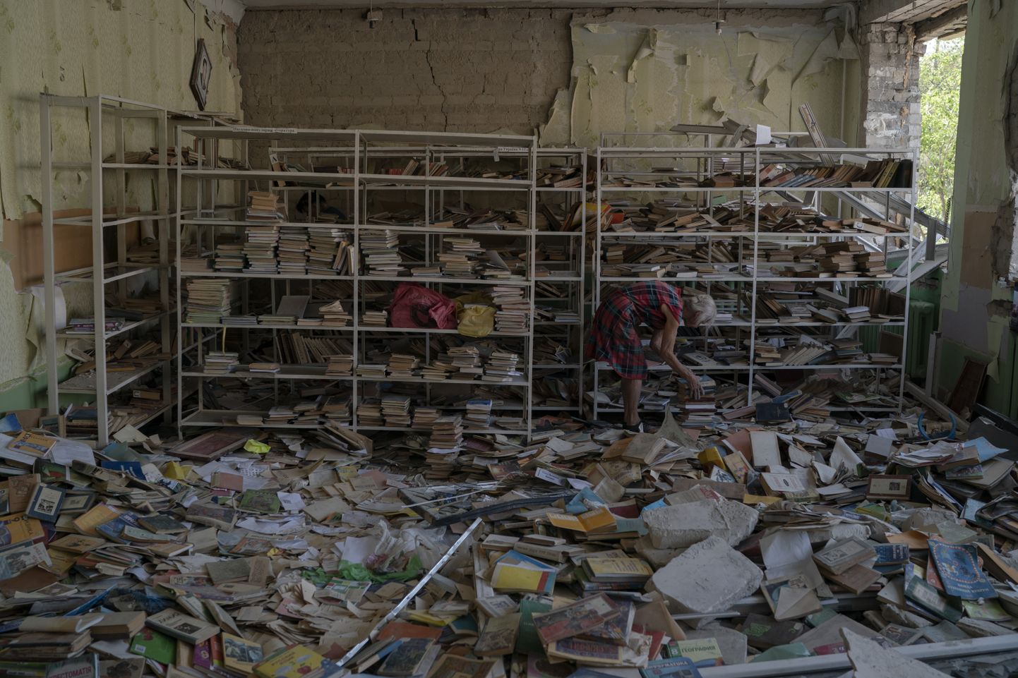 Bibliotekāre Raisa Krupčenko (81) kārto kaudzi ar grāmatām, mēģinot tās sakārtot starp gruvešiem Krievijas uzbrukuma iznīcinātajā 23. skolas bibliotēkā. Kramatorskā, Ukraina,  2022. gada 27. augusts.