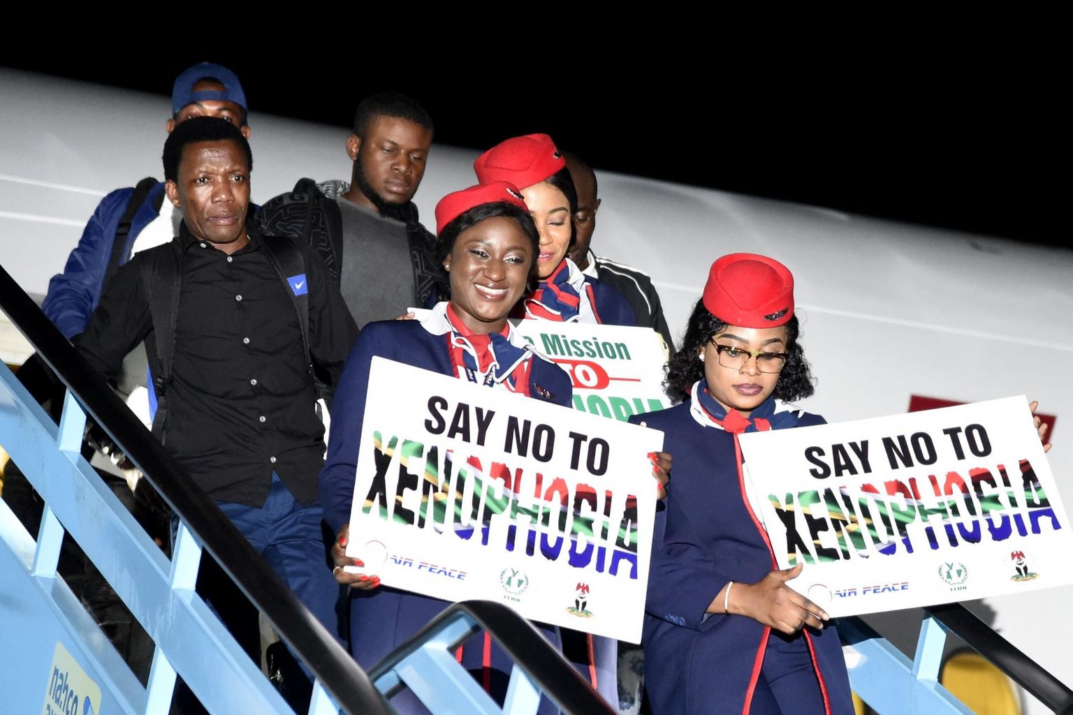 Lõuna-Aafrika Vabariigis rünnaku ohvriks sattunud nigeerlasi kodumaale toimetava lennufirma Air Peace lennusaatjad siltidega, mis kutsuvad üles ksenofoobiale vastu astuma.