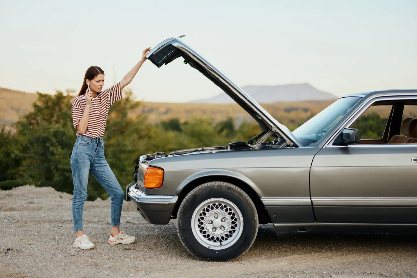 Sieviete pie salūzuša klasiska Mercedes-Benz. Ilustratīvs attēls